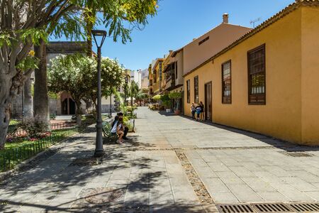 Puerto de la Cruz, Tenerife, Spain - July 10, 2019: Colourful houses and palm trees on streets. People relax and have fun on a warm sunny summer day. Have breakfast, drink coffee in a cozy cafe.のeditorial素材