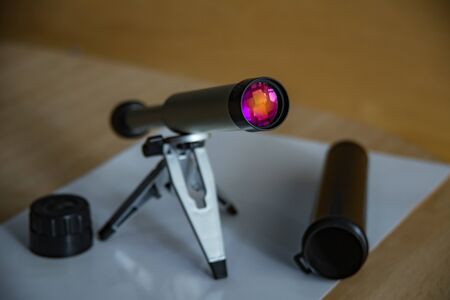 Spyglass on a small tabletop stand. Enlightenment lens beautifully shimmers colors. Black plastic case with open lid. Selective focus close up.の写真素材