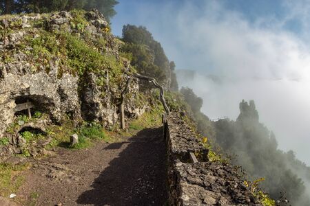 Old mountain rural trail in the mountains of the island . Evening clouds and fog crawling on the...