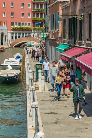 VENICE, ITALY - August 02, 2019: One of the thousands of lovely cozy corners in Venice on a clear sunny day. Locals and tourists strolling along the historical buildings and canals with moored boats.のeditorial素材