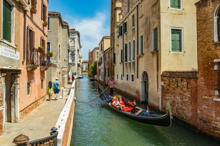 VENICE, ITALY - August 02, 2019: One of the thousands of lovely cozy corners in Venice on a clear sunny day. Locals and tourists strolling along the historical buildings and canals with moored boats.のeditorial素材