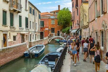 VENICE, ITALY - August 02, 2019: One of the thousands of lovely cozy corners in Venice on a clear sunny day. Locals and tourists strolling along the historical buildings and canals with moored boats.のeditorial素材