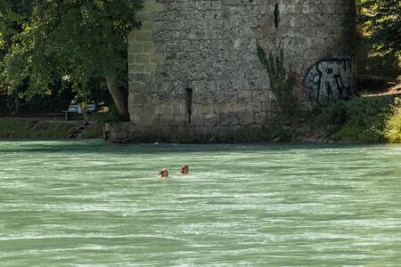 Bern, Switzerland - July 30, 2019: View of Aare river at sunny summer day. Local residents relax, sunbathe and rafting in inflatable boats along the fast flow of the river.のeditorial素材