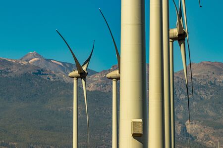 Wind power stations. A row of turbines near the seashore. Wind farm eco field. Eolic park with mount...