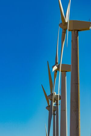 Wind power stations. Telephoto lens shot. A row of turbines near the seashore. Wind farm eco field....