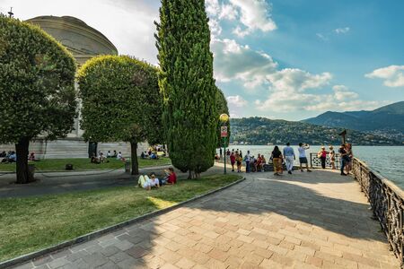 Como, ITALY - August 4, 2019: Local people and tourists on the promenade along the lake in the center of beautiful Italian Como city. Warm sunny summer day in very popular holiday destinationの写真素材