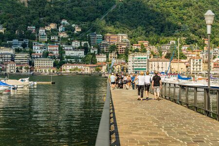 Como, ITALY - August 4, 2019: Local people and tourists on the promenade along the lake in the center of beautiful Italian Como city. Warm sunny summer day in very popular holiday destinationの写真素材