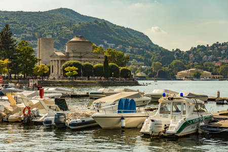 Como, ITALY - August 4, 2019: Marina in the Lake Como in the center of beautiful Italian Como city. Tempio Voltiano museum on the background. Warm sunny summer day in very popular holiday destination.のeditorial素材