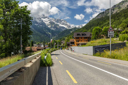 Main street in Champery village in Switzerland. Warm sunny day, blue sky with white clouds. Swiss Alps in the background.のeditorial素材