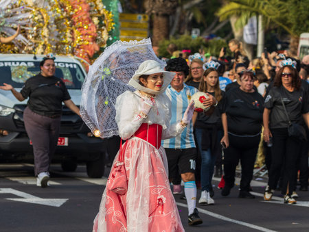 SANTA CRUZ DE TENERIFE, SPAIN - FEBRUARY 13, 2024: The Coso parade, Cavalcada - along the Avenida de Anaga, official end of Carnival. Amazing warm evening, joyful people in carnival costumes have fun.のeditorial素材