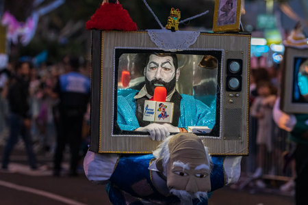 SANTA CRUZ DE TENERIFE, SPAIN - FEBRUARY 13, 2024: The Coso parade, Cavalcada - along the Avenida de Anaga, official end of Carnival. Amazing warm evening, joyful people in carnival costumes have fun.のeditorial素材