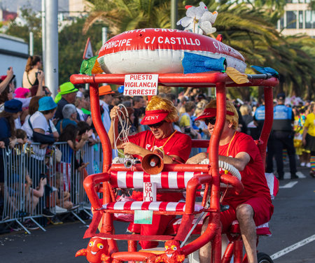 SANTA CRUZ DE TENERIFE, SPAIN - FEBRUARY 13, 2024: The Coso parade, Cavalcada - along the Avenida de Anaga, official end of Carnival. Amazing warm evening, joyful people in carnival costumes have fun.のeditorial素材