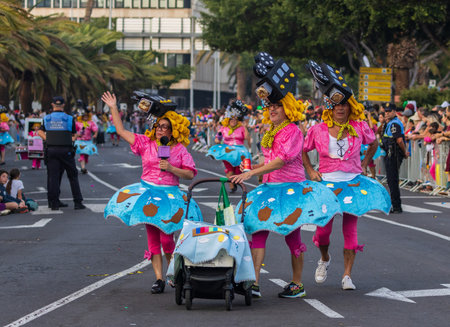 SANTA CRUZ DE TENERIFE, SPAIN - FEBRUARY 13, 2024: The Coso parade, Cavalcada - along the Avenida de Anaga, official end of Carnival. Amazing warm evening, joyful people in carnival costumes have fun.のeditorial素材