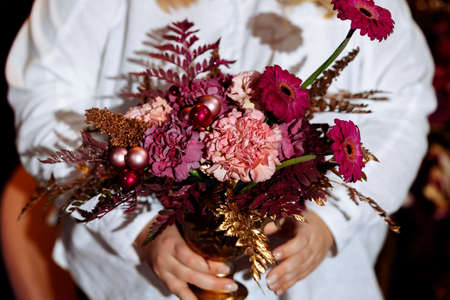 florist woman holds a flower arrangement of pink gerbera and white carnations in her hands. Selected focus and blurred backgroundの写真素材