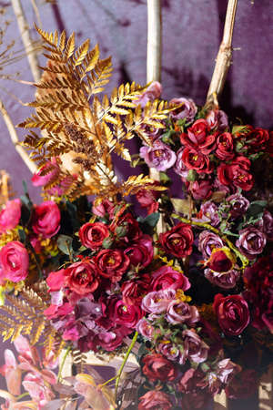 Flower arrangement on the table with pink gerbera and painted leaves gold color. Selected focus and blurred backgroundの写真素材