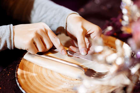 Table setting. Hands lay the napkin on the plate. Selected focus and blurred background.の写真素材
