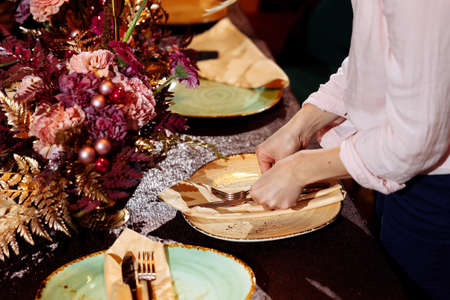 Table setting. Hands lay the napkin on the plate. Selected focus and blurred background.の写真素材