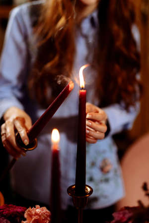 A girl lights a red candle at a party. Selected focus and blurred backgroundの写真素材