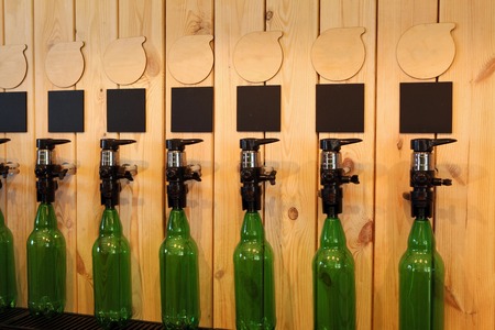 Large simultaneous spilling beer in the bar. The bar of wood. Wooden desk with a book, a beer, a lamp, a cash register. Beer fest. Beer Festival. Exclusive bar beer.の写真素材