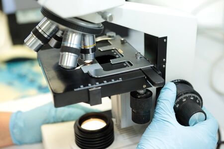 A woman and a man study the structure of the drug pellets under a microscope. The quality of the...