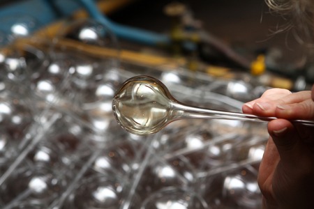 Factory of Christmas toys. The worker blows out the glass. The burner melts the glass. Decoration of...