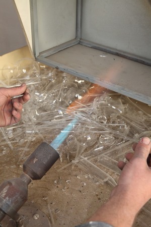 Factory of Christmas toys. The worker blows out the glass. The burner melts the glass. Decoration of a Christmas tree toy. Handmade. Manufacture of fur-tree toys. Many beautiful glass beads. Burning products in the oven.の写真素材