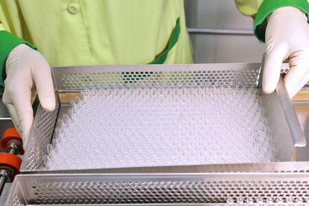 Visual control of ampoules with medicine. A woman works on an ampoule production line. Sterile...