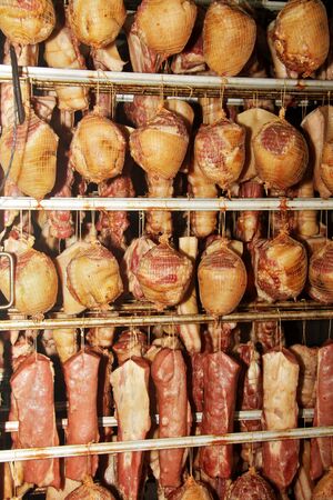 A worker at the meat processing factory, prepares sausages at the work table. Food processing and...