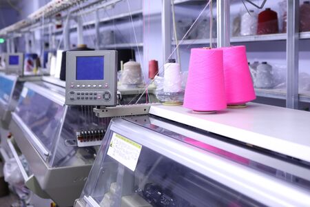 Pink spools of thread on the background of the sewing workshop. Clothing industry. Machine for the...