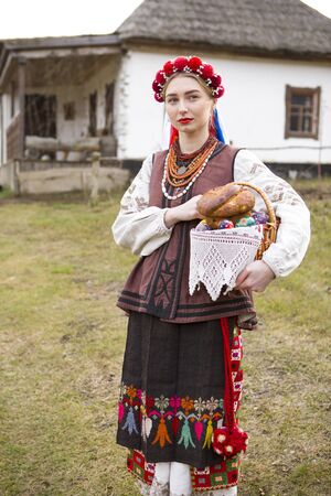 Beautiful girl in national dress with Easter and eggs in a basket. Easter holiday. In old clothes of...