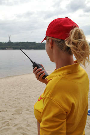Girl rescuer in a red baseball cap stands with a walkie-talkie