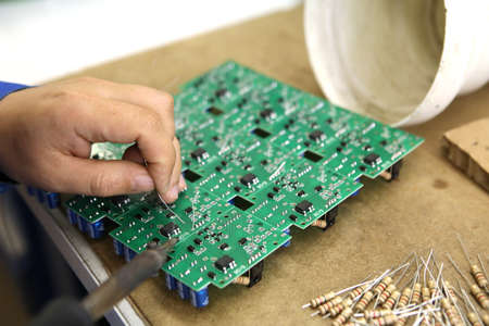 A man collects a printed circuit board. The worker solders the radio components and assembles the...