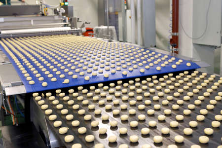 Controlling the work of huge conveyor machine producing spice cakes at the confectionary plant. Cookie production line. Innovative biscuit production..の写真素材