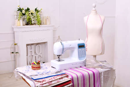 Composition from a sewing machine. Mannequin, flowers on a retro table and threads. Sewing supplies...