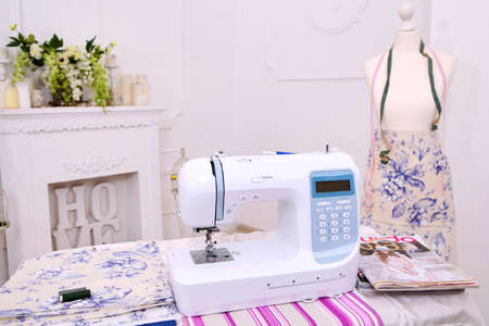 Composition from a sewing machine. Mannequin, flowers on a retro table and threads. Sewing supplies...