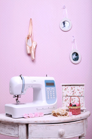 Composition from a sewing machine. Mannequin, flowers on a retro table and threads. Sewing supplies and composition with a sewing machine in the interior. With the letter M. The composition is unique for the fashion.の写真素材