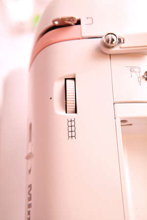 Composition from a sewing machine. Mannequin, flowers on a retro table and threads. Sewing supplies and composition with a sewing machine in the interior. With the letter M. The composition is unique for the fashion.の写真素材