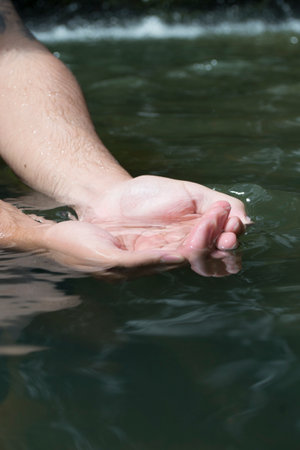 A person with hands immersed in the crystal clear watersの写真素材