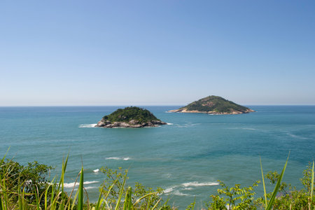 Mountains, vegetation and the ocean with clear blue waters, located in the city of Rio de Janeiro.