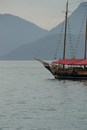 Boats in the sea of ConceiÃ§Ã£o de JacareÃ­ beach, in the background the outline of mountains and forest in Rio de Janeiro, Brazil.の写真素材