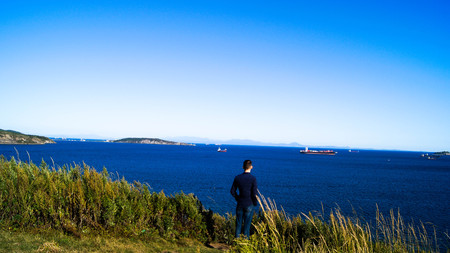 A man looks at ships on the beachの写真素材