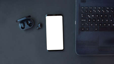 Black smartphone, laptop and headset on black background. Top view with copy space.の写真素材