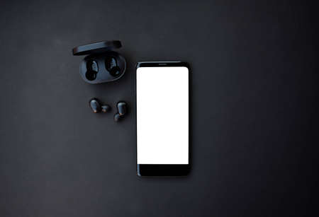 Black smartphone and headset on black background. Top view with copy space.の写真素材