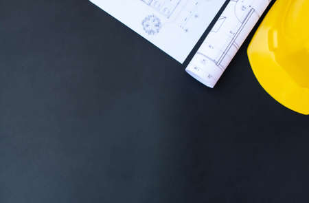 Architect working, construction desk. Project blueprints and yellow hard hat on black, copy space, top viewの写真素材