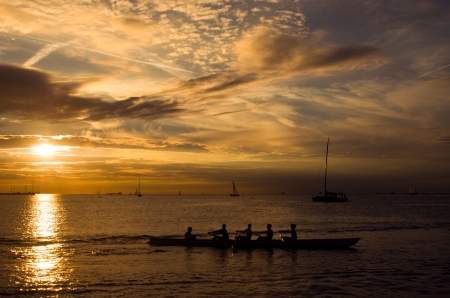 Sports team rowing in a canoe at sunsetの写真素材