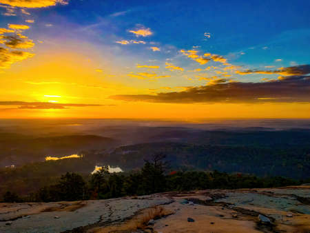 Warm glow from sunrise over fog covered forst on a partly cloud dayの写真素材