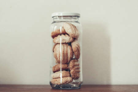 Cookies in glass jar on wooden table. Selective focus.