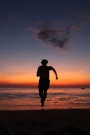 Running Silhouette On A Beach Against The Water On A Beautiful Dusk Backgroundの写真素材