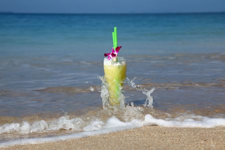 Big Glass Of Cocktail In The Sand And Being Splashed By Waves