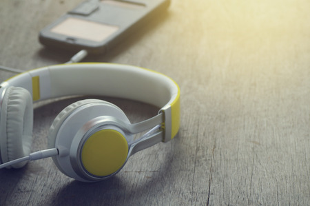 phone media portable and smart phone on dark tone. earphones and smartphone on wood table, selective focus of earphones.の写真素材